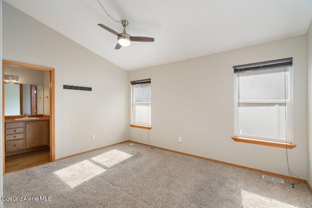 unfurnished bedroom with baseboards, visible vents, carpet floors, lofted ceiling, and a sink