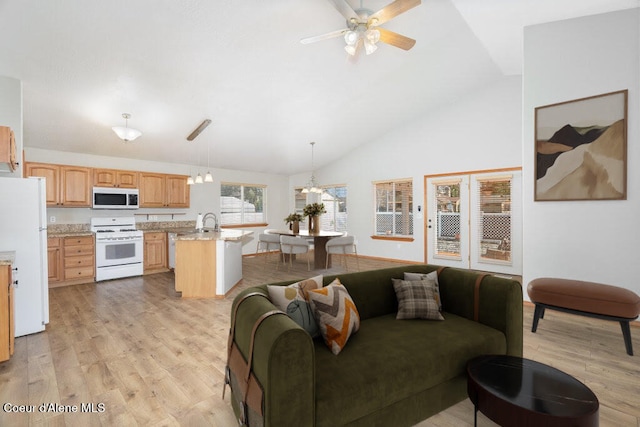 living area with light wood-type flooring, lofted ceiling, and a ceiling fan