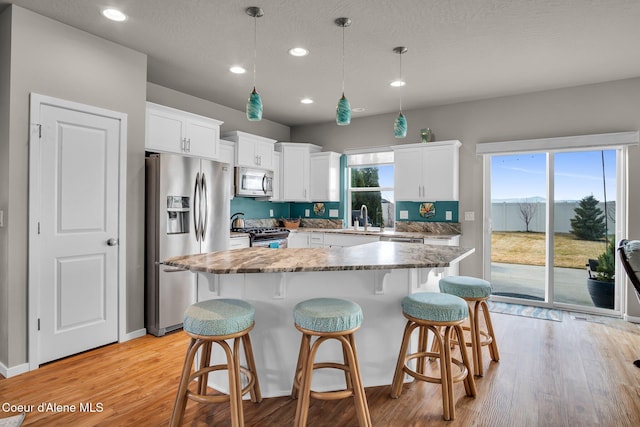 kitchen featuring a kitchen bar, white cabinetry, appliances with stainless steel finishes, and a sink