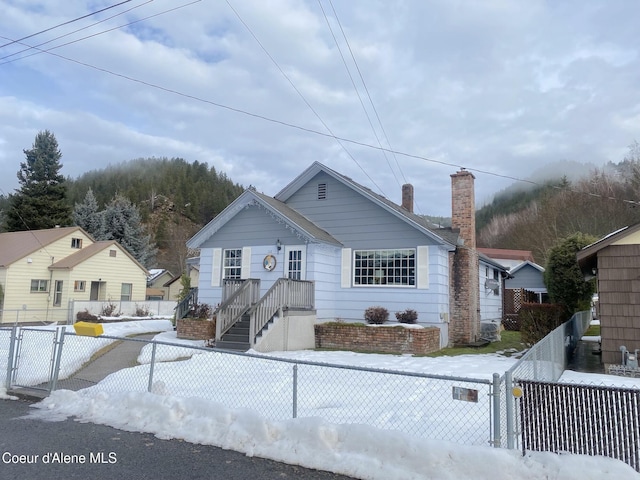 bungalow-style home with a fenced front yard, a chimney, and a gate