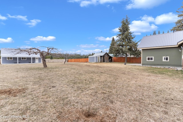 view of yard featuring a storage unit, an outdoor structure, and fence