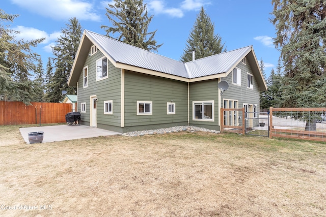 rear view of property featuring a patio area, a lawn, metal roof, and fence