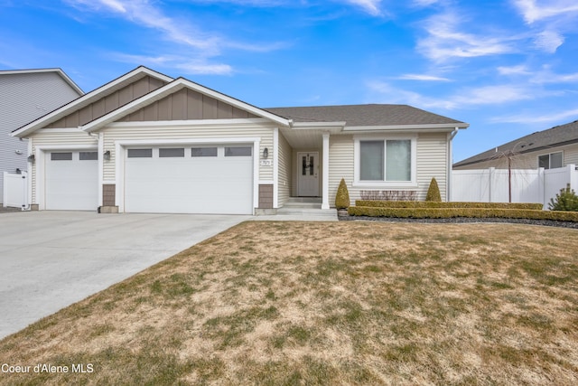 view of front of house with board and batten siding, fence, concrete driveway, a front yard, and a garage