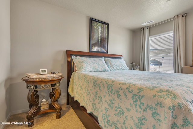 bedroom featuring baseboards, visible vents, and a textured ceiling