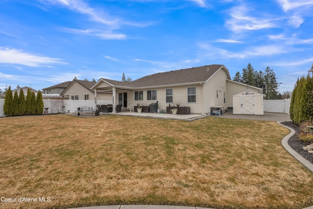 rear view of house with a storage unit, a lawn, a fenced backyard, an outdoor structure, and a patio area