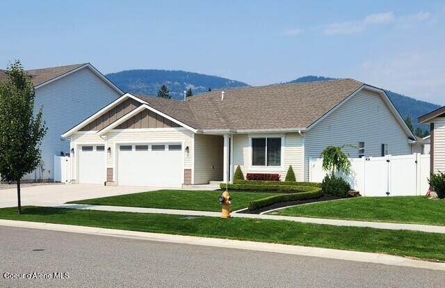 view of front of home featuring a front lawn, a gate, board and batten siding, concrete driveway, and an attached garage