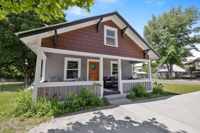 bungalow with covered porch, driveway, and fence