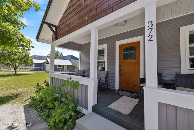 doorway to property featuring a porch and a yard