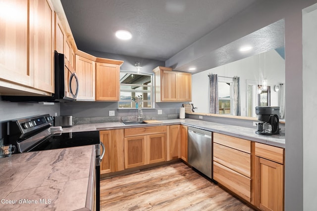 kitchen with light countertops, light brown cabinetry, a sink, light wood-style flooring, and appliances with stainless steel finishes