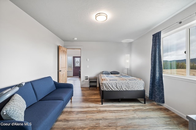 bedroom with baseboards, wood finished floors, and a textured ceiling
