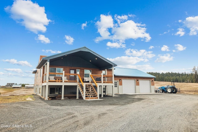 view of front facade featuring gravel driveway, stairs, a garage, a deck, and an outdoor structure