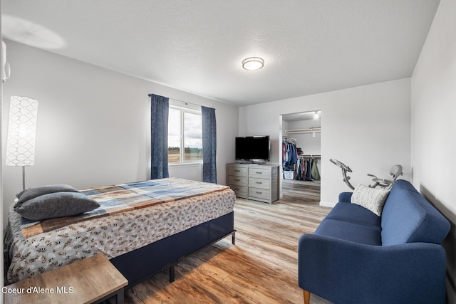bedroom featuring a walk in closet, a closet, and light wood-type flooring