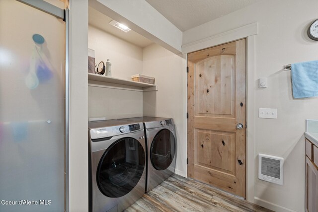 laundry room with washer and clothes dryer, baseboards, visible vents, laundry area, and wood finished floors