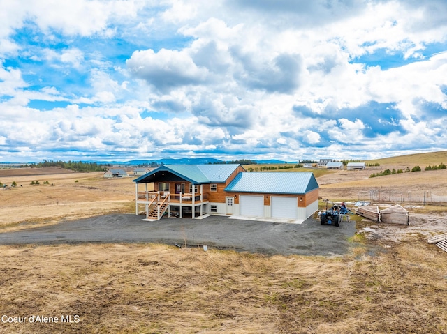 back of house with metal roof, dirt driveway, and a rural view