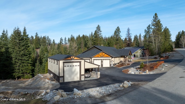 view of front facade featuring aphalt driveway, a garage, and a wooded view