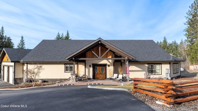 view of front of property featuring aphalt driveway, a garage, and roof with shingles