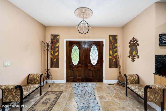 foyer featuring a notable chandelier, visible vents, and baseboards