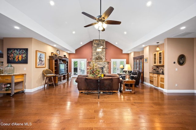 living area with baseboards, high vaulted ceiling, hardwood / wood-style floors, and a ceiling fan