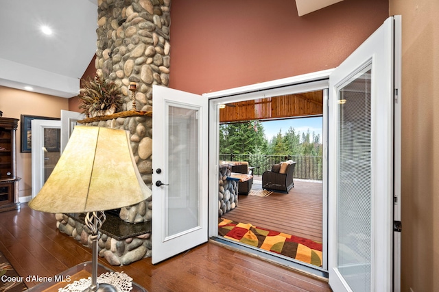 doorway to outside with high vaulted ceiling and hardwood / wood-style floors