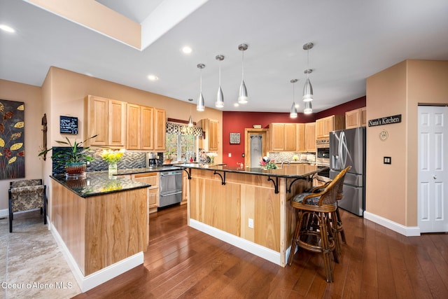 kitchen with a breakfast bar area, dark wood-style floors, light brown cabinets, decorative backsplash, and appliances with stainless steel finishes