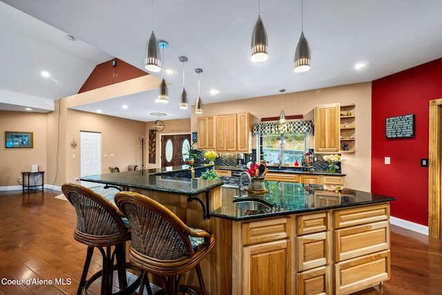 kitchen featuring vaulted ceiling, dark wood-style floors, a large island with sink, and a sink