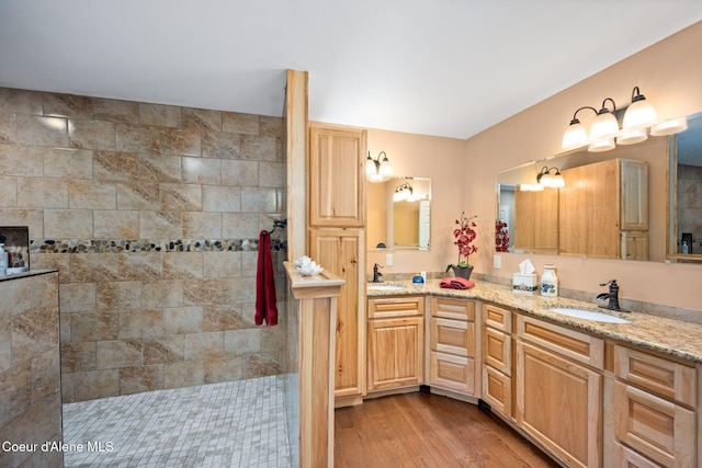 full bath featuring wood finished floors, a walk in shower, double vanity, and a sink