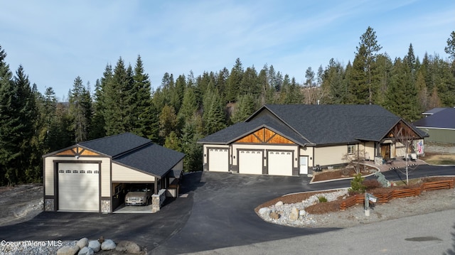 view of front of property with a forest view, a garage, and driveway