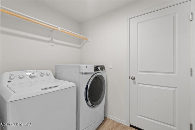 laundry area featuring washer and dryer, laundry area, baseboards, and light wood finished floors