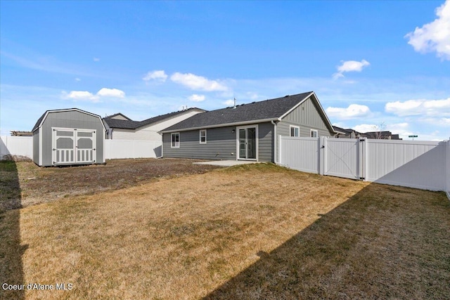 back of house with a fenced backyard, a storage unit, a yard, and a gate