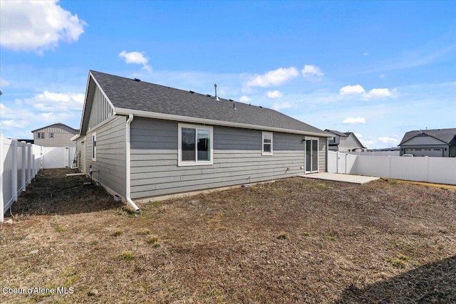 rear view of property with a shingled roof, a fenced backyard, and a patio area