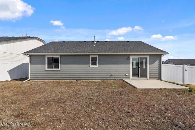 back of house with a shingled roof, a lawn, a fenced backyard, and a patio area