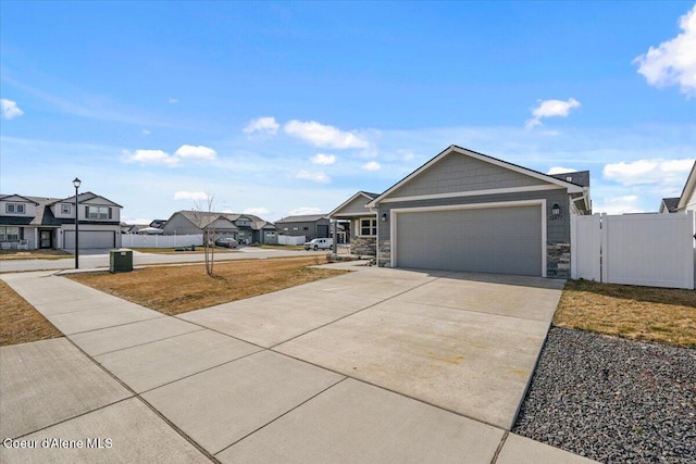 view of front of property featuring concrete driveway, a garage, fence, and a residential view