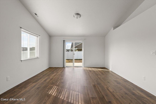 empty room featuring dark wood finished floors, lofted ceiling, baseboards, and visible vents