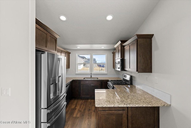 kitchen with dark wood-type flooring, light stone countertops, recessed lighting, stainless steel appliances, and a sink