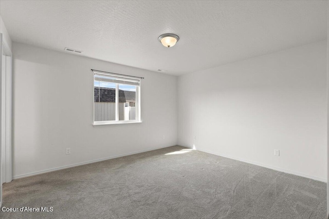 spare room with baseboards, visible vents, carpet floors, and a textured ceiling