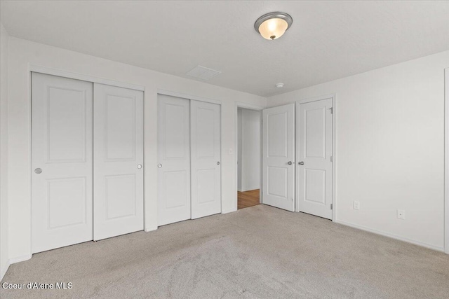 unfurnished bedroom with multiple closets and carpet