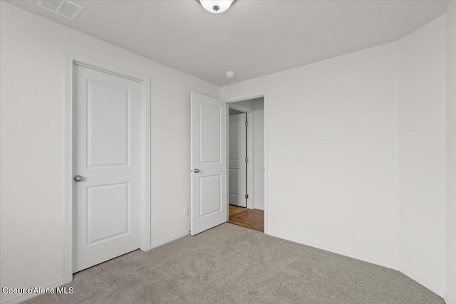 unfurnished bedroom featuring visible vents, baseboards, and carpet