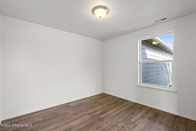 unfurnished room with visible vents, dark wood-type flooring, and baseboards