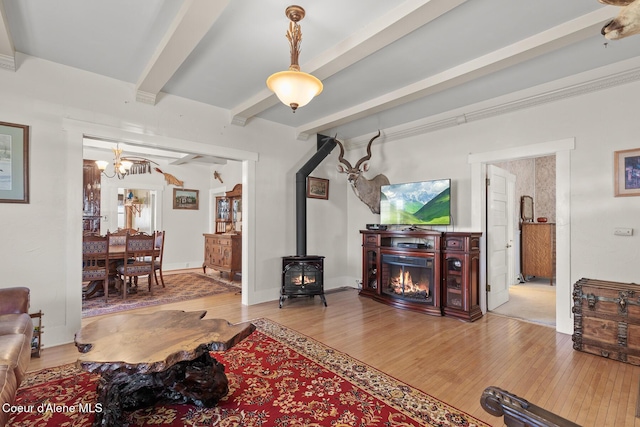 living area featuring beamed ceiling, baseboards, an inviting chandelier, and wood finished floors