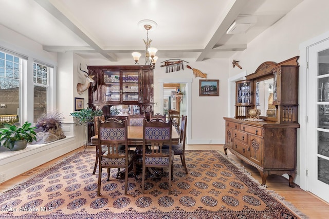 dining area featuring light wood-type flooring, beamed ceiling, coffered ceiling, an inviting chandelier, and baseboards