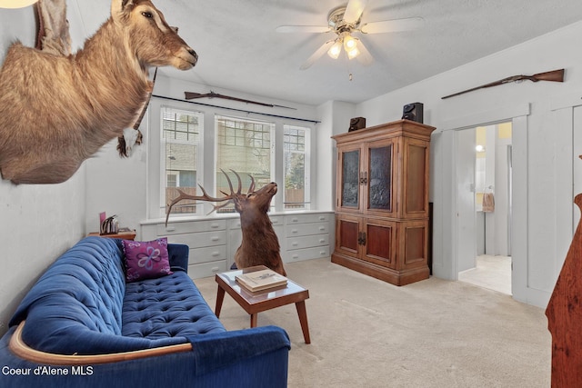 living area featuring light colored carpet and ceiling fan