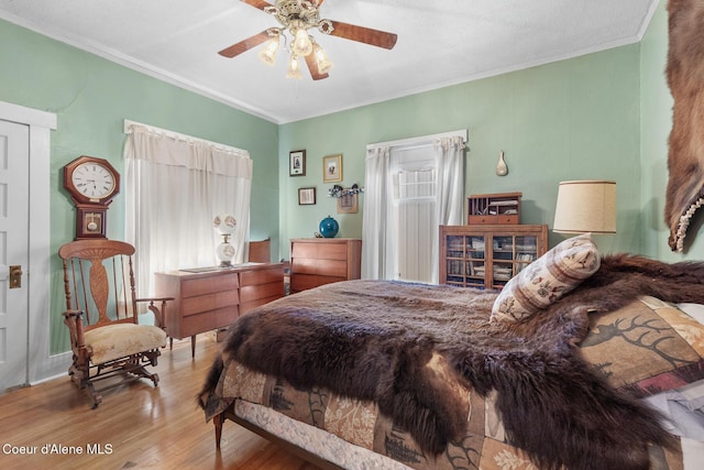 bedroom featuring a ceiling fan, wood finished floors, and ornamental molding