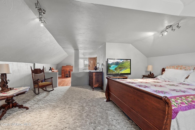 bedroom featuring lofted ceiling, rail lighting, and light carpet