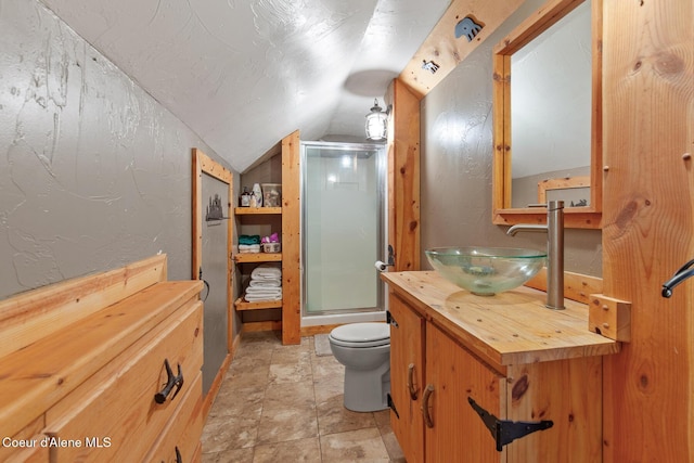 full bath featuring toilet, vaulted ceiling, a stall shower, a textured wall, and vanity