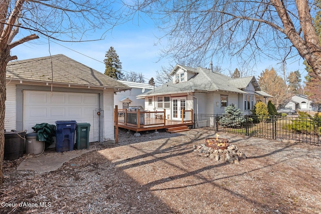 view of side of property featuring an outbuilding, a deck, an outdoor fire pit, fence, and a garage