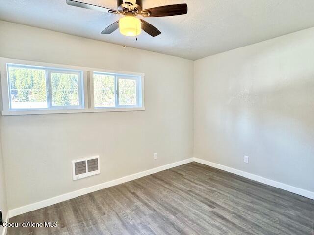 empty room featuring visible vents, baseboards, and wood finished floors