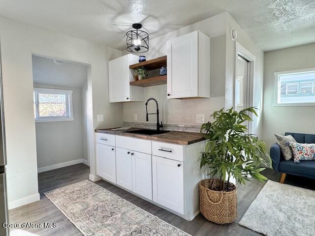 kitchen featuring a sink, light wood-type flooring, white cabinetry, wood counters, and open shelves