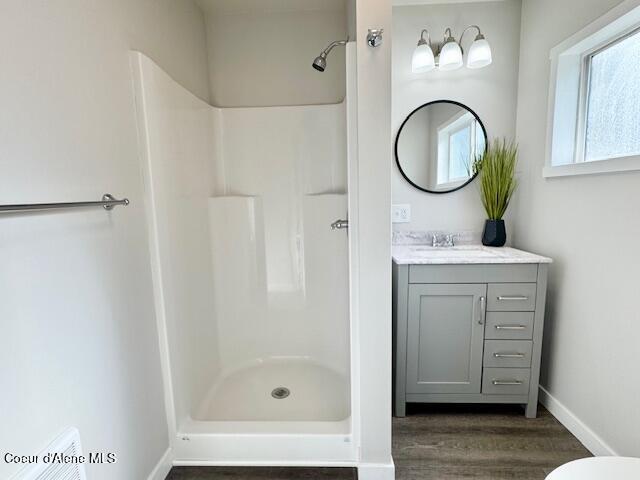 full bath with baseboards, vanity, walk in shower, and wood finished floors