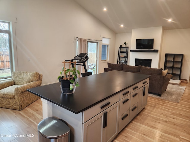 kitchen featuring light wood-style floors, dark countertops, open floor plan, and a fireplace