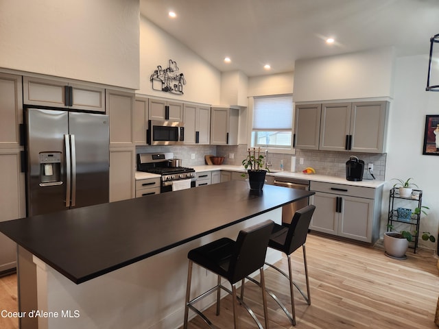 kitchen featuring stainless steel appliances, gray cabinetry, and light wood finished floors